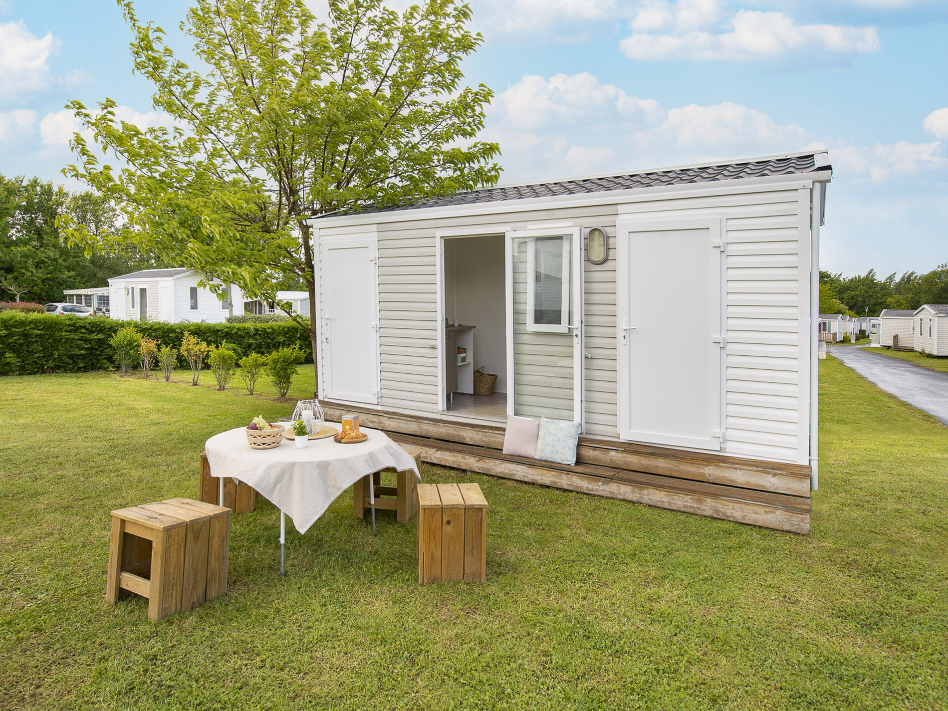 Mobil-home avec terrasse et jardin verdoyant.