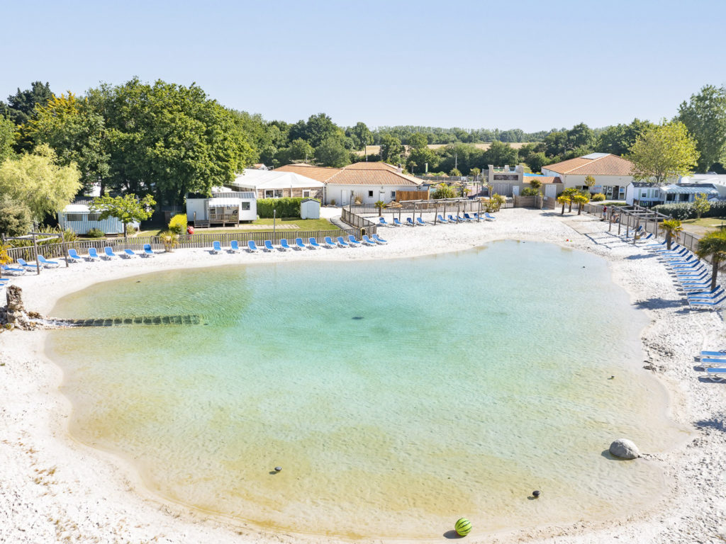 Lac artificiel avec plage et chaises longues.
