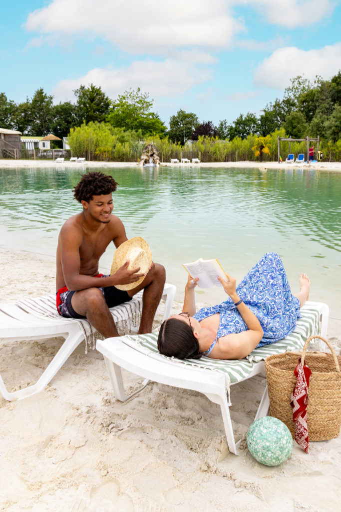 Deux personnes détendues sur des chaises longues, plage.