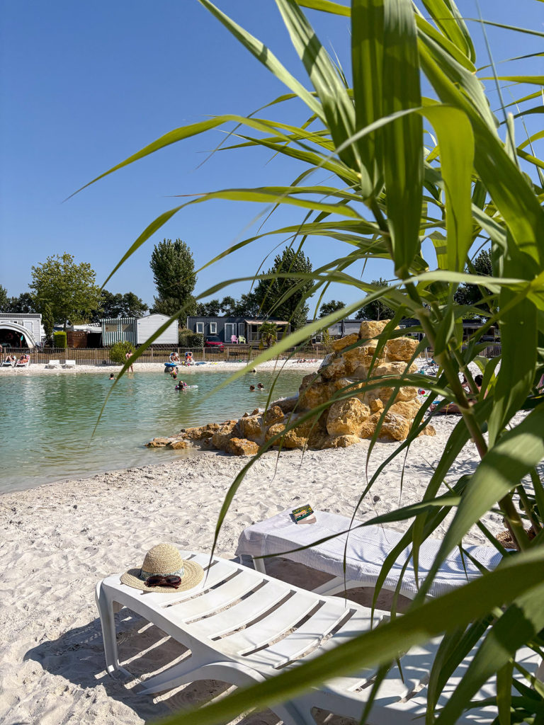 Plage artificielle avec transats et piscine naturelle.