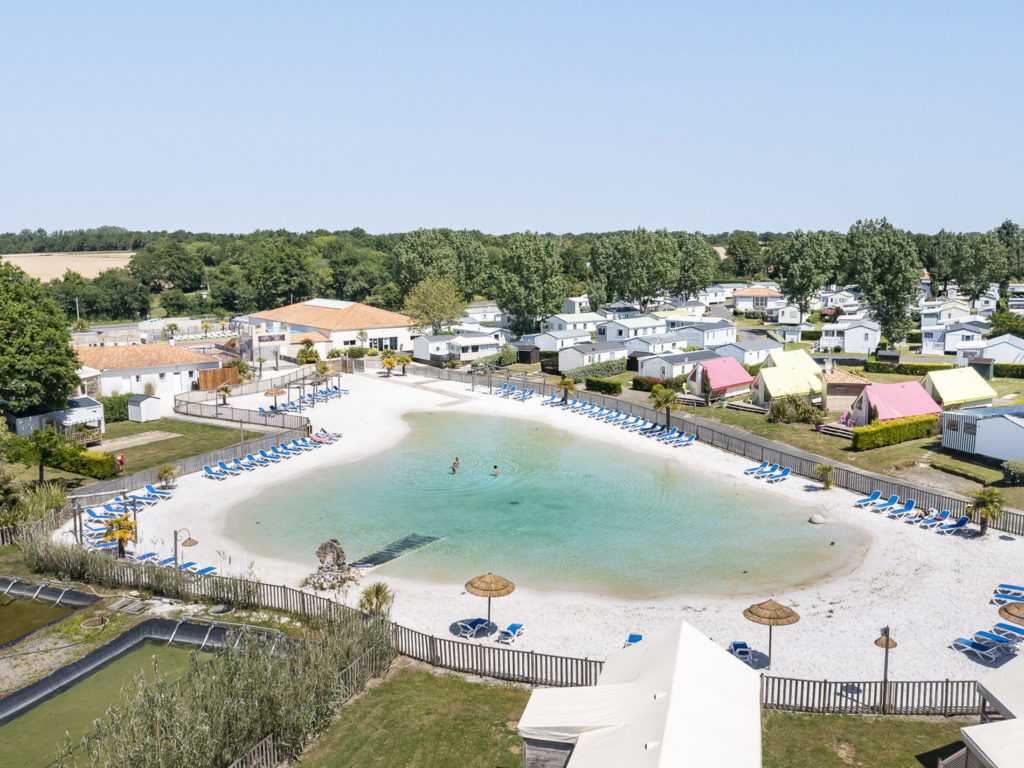 Vue sur plage et mobil-homes en camping.