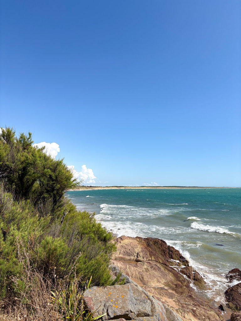 Côte rocheuse et océan sous ciel bleu limpide.